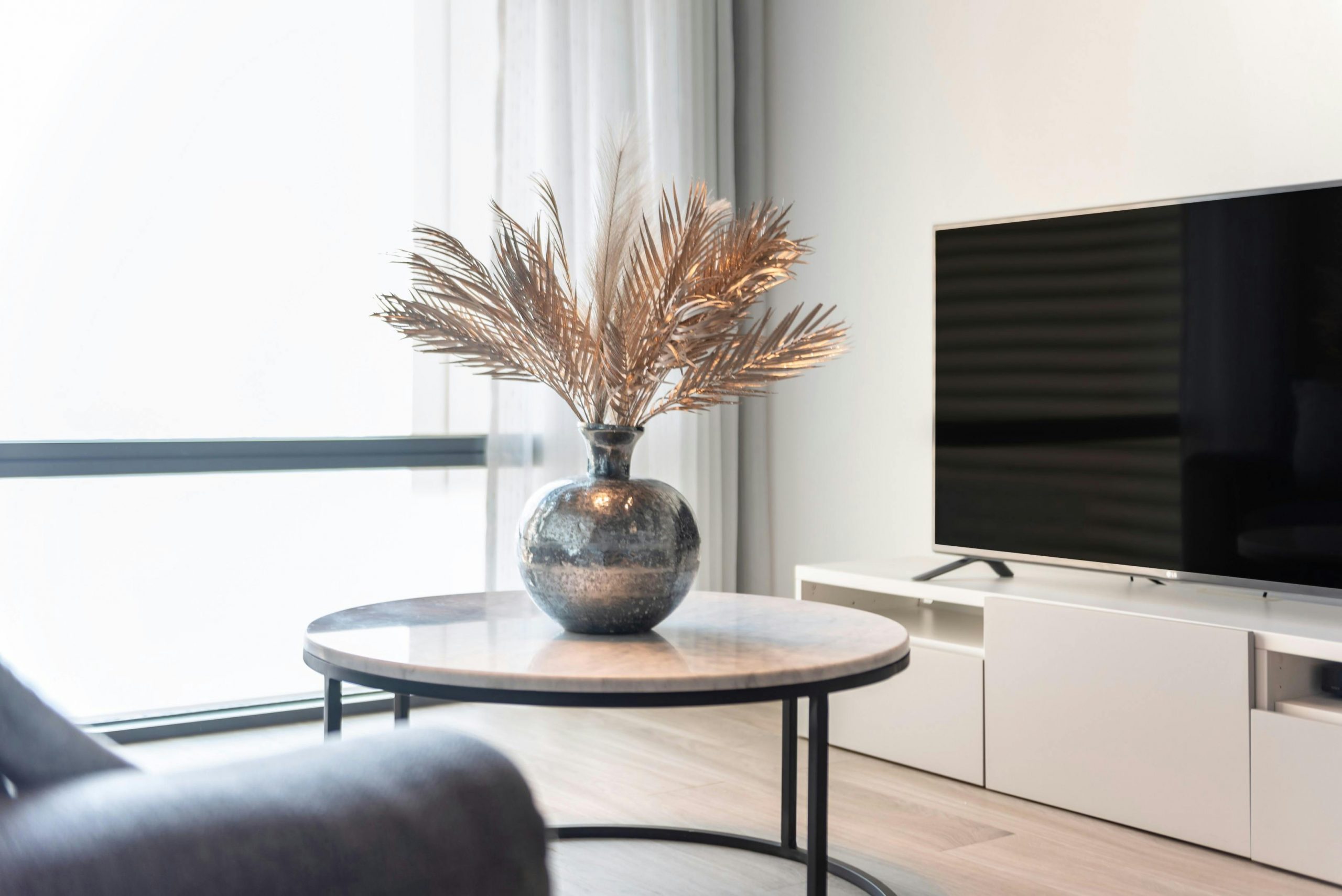 Stylish living room featuring a TV, table, and a vase with decorative leaves.