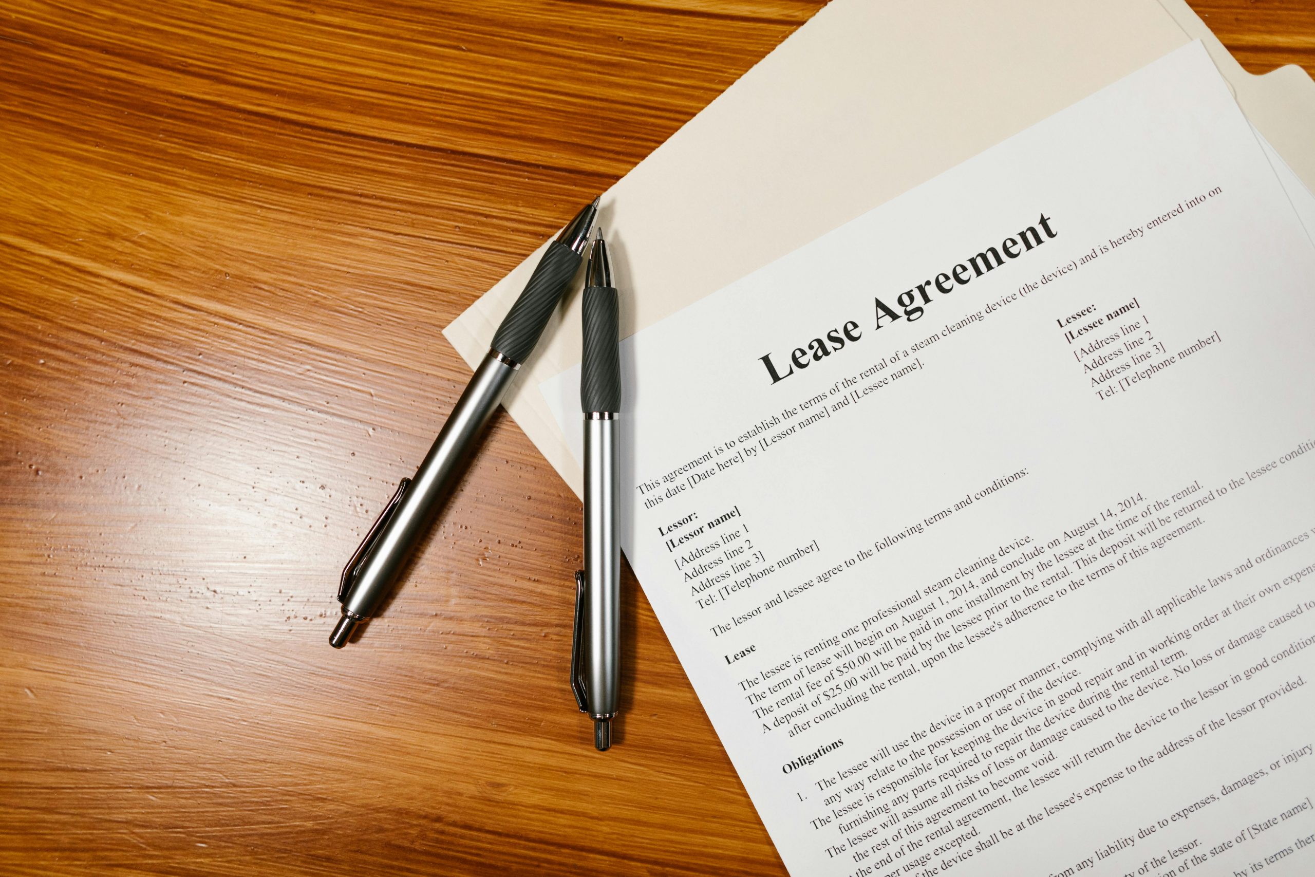 High-angle view of a lease agreement and pens on a wooden desk.